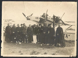 Fotografia grup de preveres davant d'un avio.